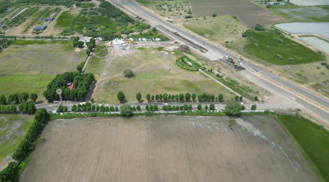 Actual aerial site photograph showing the roadside entrance and tree-lined boundary